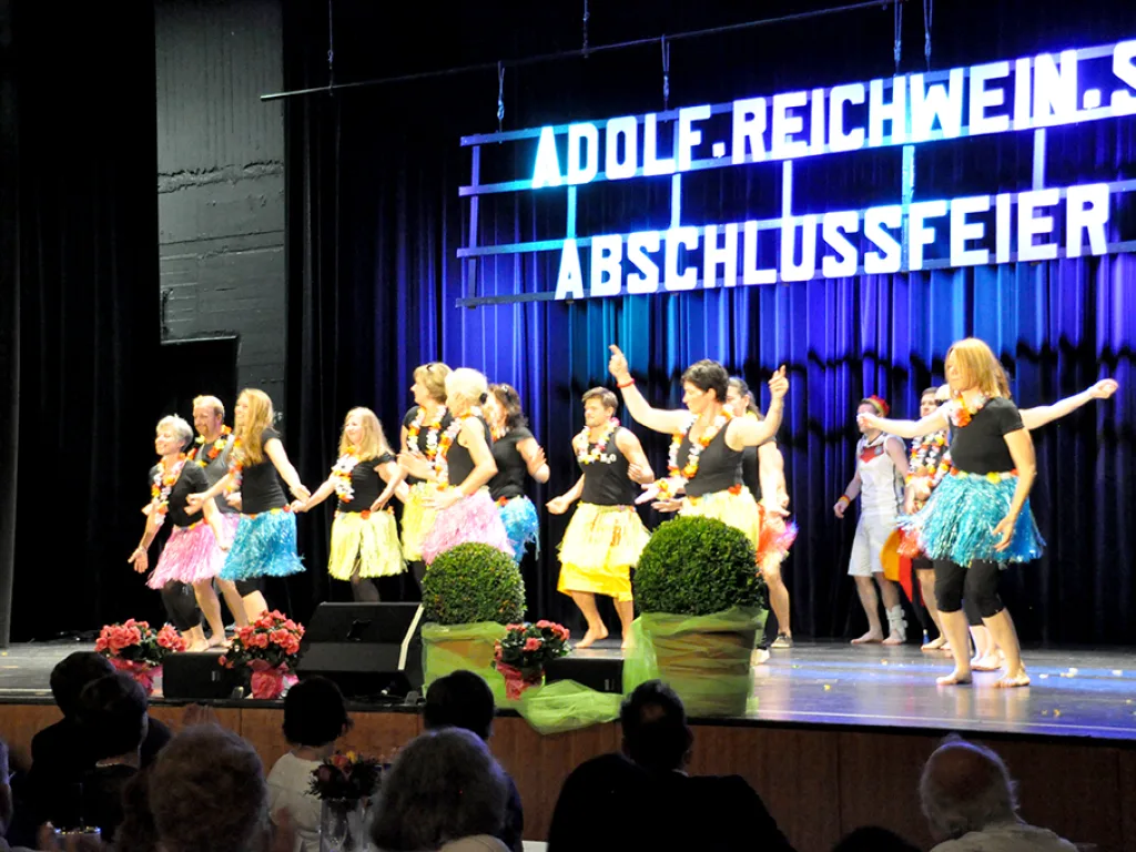 Tanzgruppe in bunten Röcken auf der Bühne.